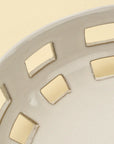Close-up of the Indaba Cypress Fruit Bowl L, a white ceramic kitchen piece featuring square cut-out patterns along the rim, displayed on a light beige countertop.