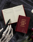 “People I Plan to Haunt” diary by Hachette on a desk with skeleton hand, styled with spooky stationery accessories.