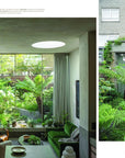 A modern living room with large windows and lush plants features in “Outside In: Thoughtful Interiors” by Random House, showcasing how natural light connects indoor spaces to gardens—perfect inspiration for any beautiful home.
