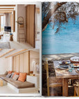 The open book "Great Escapes Mediterranean" by Ingram Book Company shows inviting sunlit hotel interiors on the left and an al fresco dining table with a view of the blue sea and cliffs on the right.