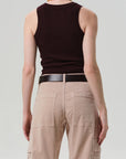 A person faces away from the camera wearing the Citizens Of Humanity/AGOLDE Isabel Rib Tank F25 in dark brown, styled with a black belt and light beige cargo pants. The background is plain and light.