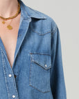 A person wears a Citizens Of Humanity/AGOLDE cropped western shirt with a front pocket and gold necklaces with round pendants, shown from shoulders to chest against a plain background.