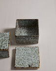 The Whisper Lidded Box by Accent Decor, featuring a square, speckled ceramic design in gray and brown, sits on a light surface with its matching lid beside it—ideal as stylish jewelry storage or a decorative home accent.