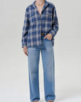 Woman in a marina plaid vintage long button-up shirt by Citizens of Humanity, wide-leg jeans, and black sandals.