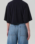 A person is shown from the back against a plain light background wearing the Citizens Of Humanity/AGOLDE Lowen Polo Shirt and high-waisted, light blue denim jeans.