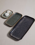 Three Accent Decor Starling Trays in different sizes are arranged diagonally on a light surface. The smallest tray holds two powdered cookies, while the other two decorative trays are empty.