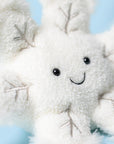 The Amuseable Snowflake by Jelly Cat Inc. is a soft, plush toy featuring embroidered silver branches, black button eyes, and a smiling mouth—perfect for adding charm to any light blue setting.