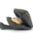 Amuseables Michelle Mussel by Jelly Cat Inc. is a plush toy shaped like a gray clam with a smiling, pearl-like face and two soft flipper-like feet, shown against a white background.