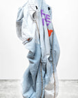 A light blue CanyonKid Home/Stud Flap/Snap denim jacket by Free City (sparrow, LLC) with brown stitching, bold purple FREECITY text, and an orange heart hangs against a white background marked "art commerce.
