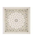 The Silk Bandana by The Great Inc. is a white silk accessory adorned with black and gold paisley and floral motifs, a bold central circular floral design, and ornate borders—a timeless homage to vintage bandanas.