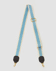 The Clare Vivier Crossbody Strap S24 is a beige nylon webbing strap with a blue and white checkered pattern, black leather-reinforced ends, gold swivel clasps, and hardware—combining style and durability.