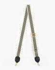The Clare Vivier Crossbody Strap S24 features black and white checkerboard nylon webbing, gold hardware, black leather trim at the ends, and swivel hooks on both sides, shown laid flat on a white background.