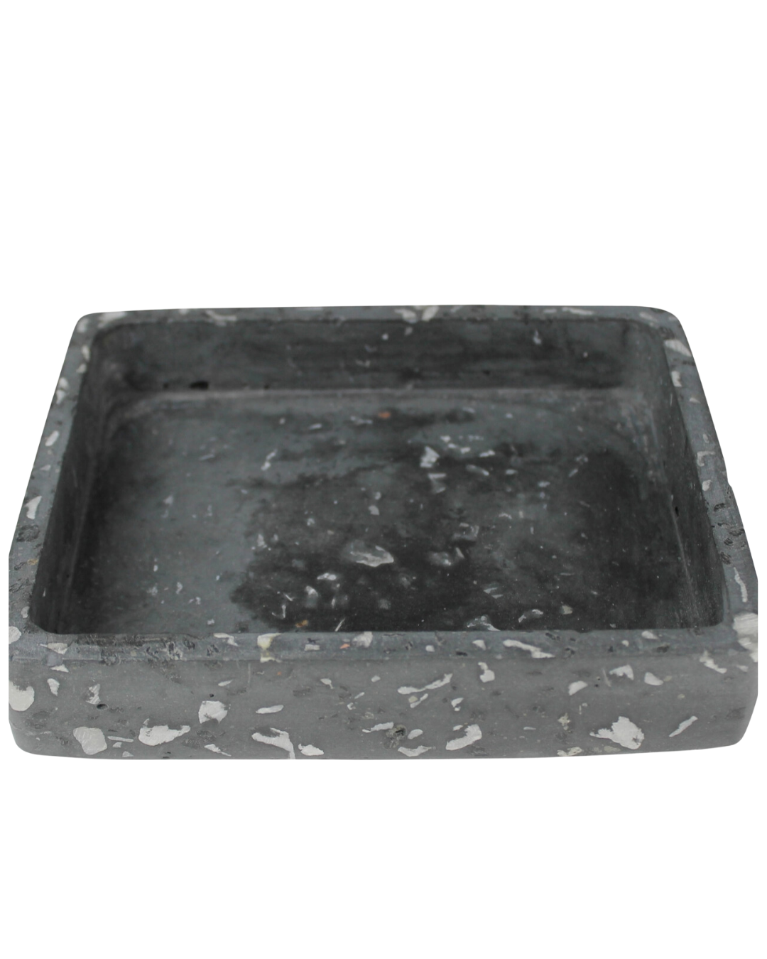 A rectangular terrazzo tray black with a flat bottom and raised edges, showing signs of wear in a Scottsdale Arizona bungalow, and several white speckles scattered across its surface.