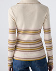 A person facing away from the camera wears the Desiree Tee by AMO Denim, a cream-colored ribbed top with horizontal pink, yellow, and brown stripes and a classic collar, paired with blue jeans against a plain background.