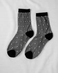 Sheer Dot Socks by Unified: sheer black socks with small white dots and solid black toes, heels, and cuffs—stylish women’s accessories displayed flat on a white surface.