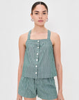 A person wears the Leah Top In Stripes by Alex Mill—a green and white vertically striped sleeveless button-down—paired with matching lightweight shorts, standing against a plain light background.