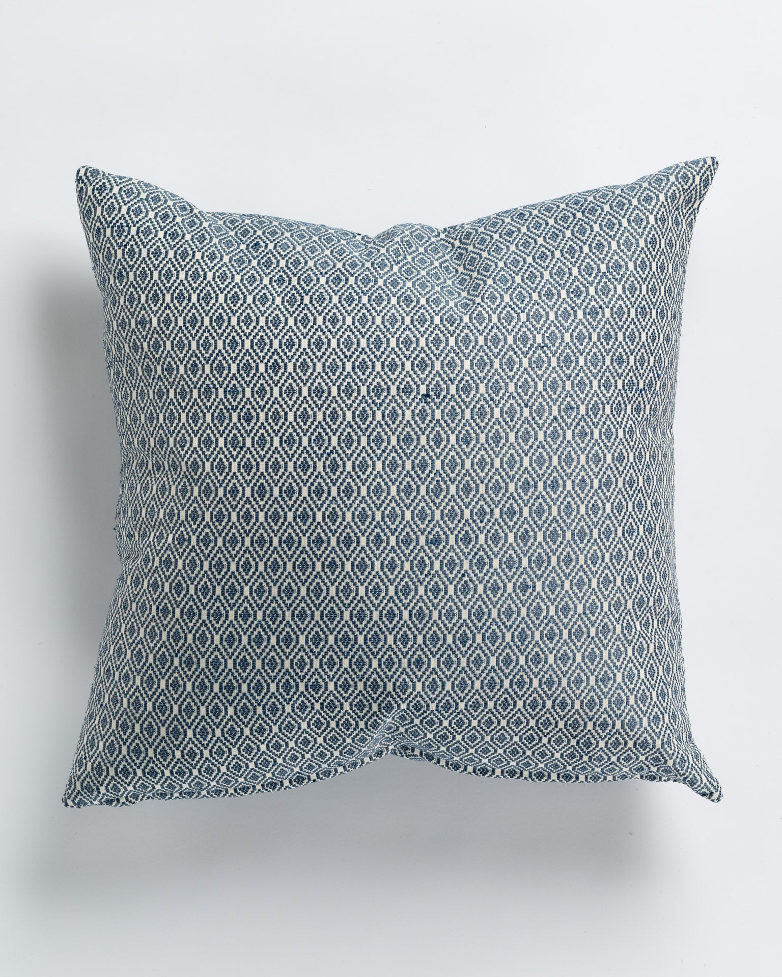 A square decorative pillow featuring a blue and white geometric pattern, displayed against a plain white background in a Scottsdale Arizona bungalow.
