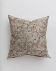 A Gabby Cherry Blossom Taupe Pillow in 26x26 inches with a floral pattern in muted pink and orange hues on a gray background, photographed against a white surface in a Scottsdale, Arizona bungalow.