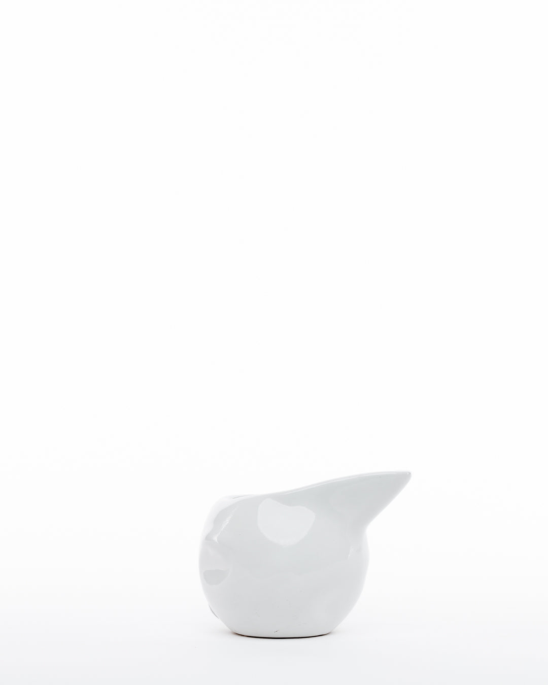 A minimalistic white ceramic pitcher, crafted using traditional techniques, features a smooth, rounded body and a small spout. The design is modern and simplistic, set against a plain white background. The Gravy Boat 374 by Montes Doggett is positioned slightly off-center and is the only object in the image.