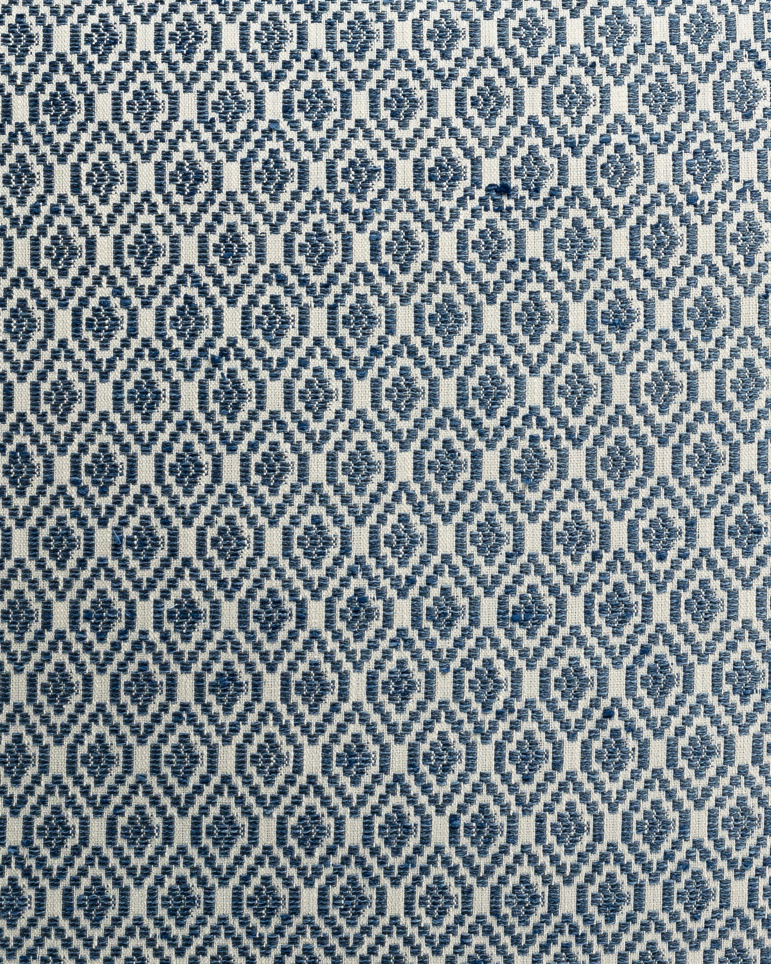 A close-up of a fabric with a repetitive geometric pattern in shades of blue and white.