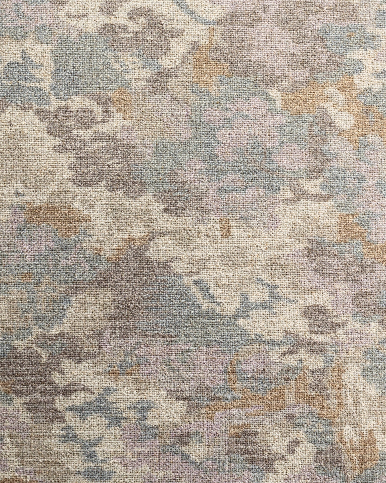 Close-up of a textured carpet in a bungalow with a floral pattern in muted shades of blue, beige, and purple Gabby Imperial Pastel Pillow 26x26.
