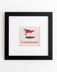 A framed acrylic illustration featuring a red golf flag with "L.A.C.C." written on it, positioned in a hole on a green. Below the illustration, text reads "The Los Angeles Country Club." The frame is black, with the print centered and surrounded by a white mat. This product is called the Art Square Black Frame from Match South.