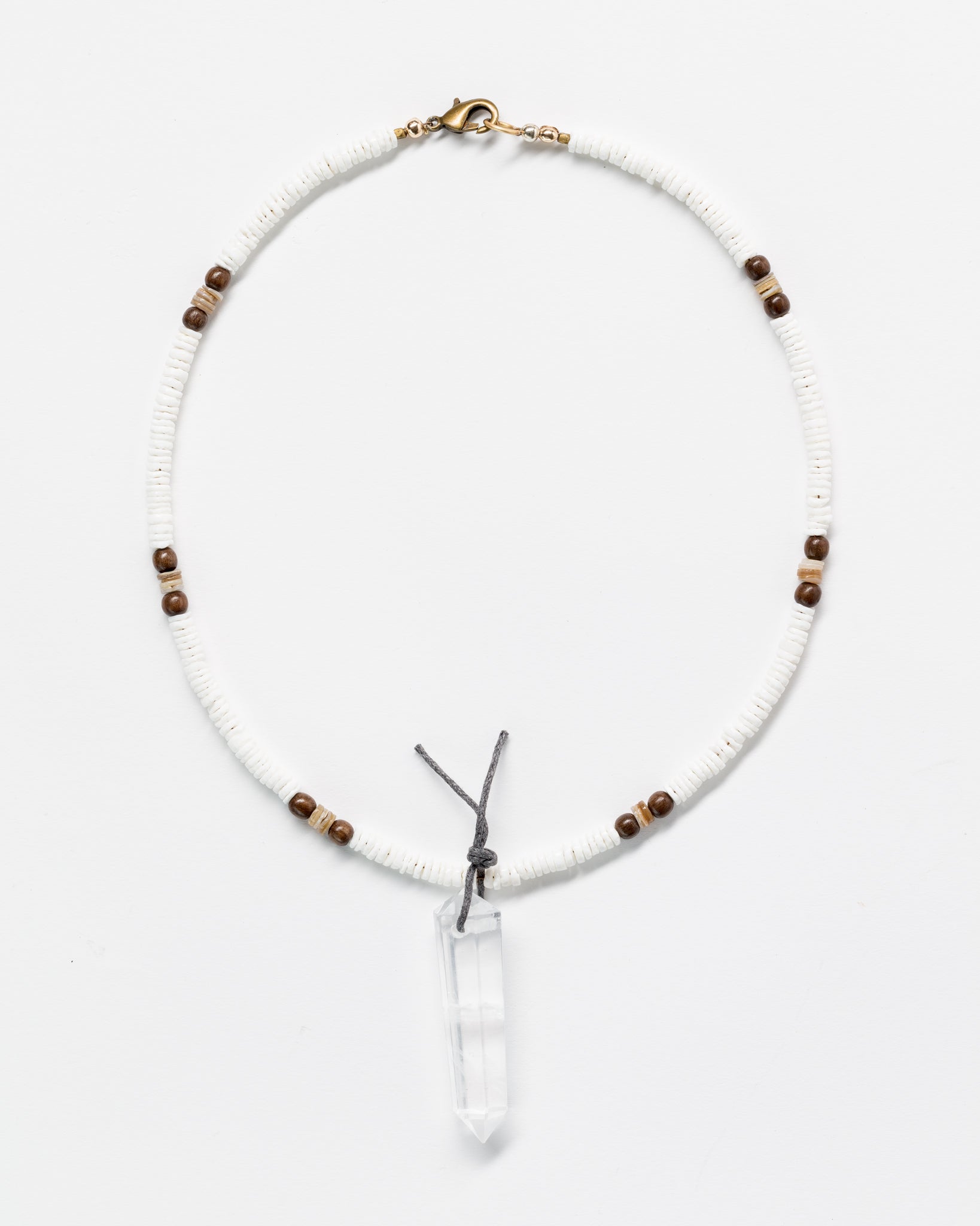 A White Designs By Raya Necklace featuring a clear quartz crystal pendant, strung with white and brown Arizona-style beads, displayed against a white background.