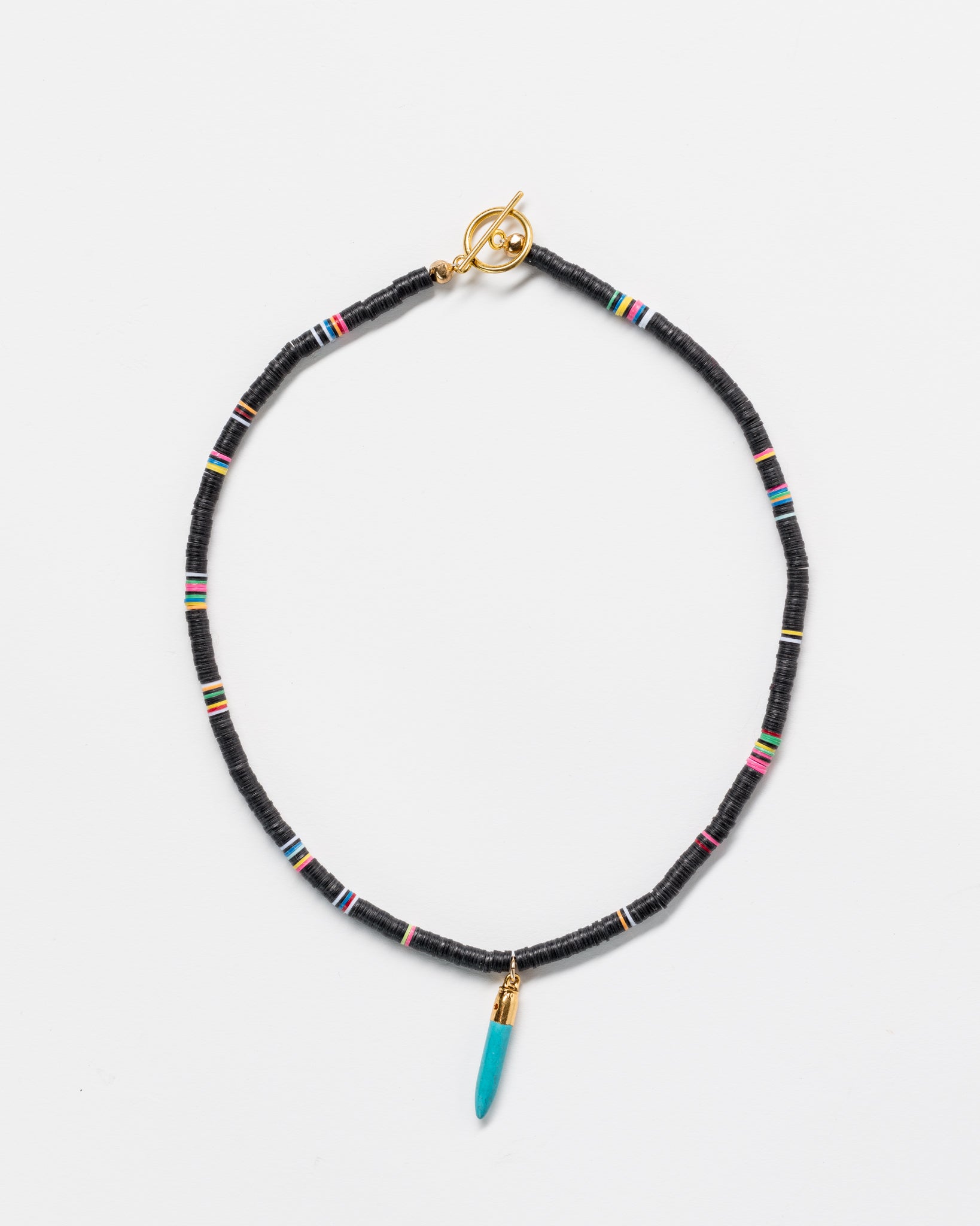 A Designs By Raya necklace made of black beads with colorful Arizona-style stripes, featuring gold accents and a turquoise pendant, displayed on a white background.