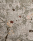 Close-up of a Cherry Blossom Taupe Pillow 26x26 in a Gabby bungalow with muted floral patterns and scattered stain marks.