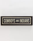 The Street Sign In Black by Spicher And Company features "COWBOYS AND INDIANS" in bold letters with a simple black frame—ideal wall decor for fans of classic vintage signs, displayed against a plain white background.