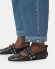A person wearing CLOSED Rhannon Denim barrel-fit jeans in a vintage wash, paired with black flat shoes featuring two straps adorned with large silver beads.