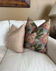 Two decorative Rennah Collective Iris Pillow 22x22 throw pillows rest on a white couch: one features light beige stripes in polyester-linen, the other displays pink flowers with green leaves. A lamp and framed art are seen in the background.