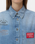 A woman wears the CLOSED Oversized Shirt featuring metallic buttons, a pointed collar, a red "CLOSED PRODUTTORE DI JEANS DAL 1978" patch, partial text above the pocket, and Italian craftsmanship.