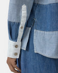 A close-up of a person wearing the CLOSED Rugby Shirt with color-blocked lightweight denim, white cuff with three buttons, and matching denim pants. Their hand is relaxed at their side.