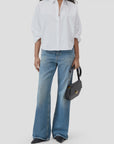 A person wears the CLOSED Gathered Shirt in white, blue wide-leg jeans, black pointed-toe shoes, and holds a black handbag against a plain background.
