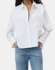 A person wearing the CLOSED Gathered Shirt, a relaxed-fit organic cotton blouse with sleeves rolled up, paired with light blue jeans and standing hands in pockets against a plain background.