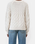Someone wearing the CLOSED Crew Neck Cable Knit sweater in white organic cotton and blue jeans is shown from the back against a plain white background.