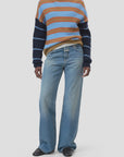 A person wears the CLOSED Crewneck LS Knit sweater, featuring colorful blue, orange, and beige stripes, styled with loose blue jeans and black shoes, standing against a plain light background.