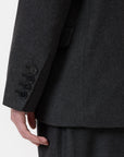 A close-up shows a person wearing the CLOSED Fitted Doublebreasted Blazer in dark gray, highlighting the sleeve with four black buttons and part of their hand against a plain, light background.