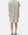 A person stands facing away, wearing the CLOSED Turn-up Shirtdress—a loose, knee-length cotton dress with vertical black and white stripes, collar, mother-of-pearl buttons, and short sleeves—paired with flat sandals against a plain white background.
