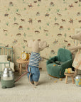 Two Maileg toy mice in a miniature room: one vacuums by a Maileg Folding Chair, while the other mouse in a dress stands nearby. The cozy Mouse hole Farmhouse features a bed, clock, crumbs, and playful animal-themed wallpaper.