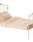 The Maileg Furniture metal bed by Maileg features gold accents, a polka dot pillow, and a pastel ruffled blanket—ideal for Maileg Mouse or dollhouse play. Shown against a plain white background.