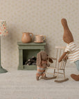 Maileg stuffed bunnies in a cozy miniature room featuring a rocking chair, lamp, and fireplace for Bungalow display.