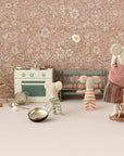 The Maileg Triplet Mice by Maileg snuggle in a tiny, vintage-themed kitchen with a stove, rocking chair, pans, and eggs; one mouse stands on a chair flipping a fried egg while the others look on.