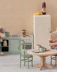 Two Maileg mice enjoy ice cream in a miniature kitchen with the Maileg Fridge, tiny food items, cups, and pastel wallpaper—a charming scene perfect for your Maileg Mouse hole Farmhouse display.