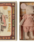 The Maileg Big Sister Mouse in pink pajamas lies on cozy bedding with a checked mattress, tucked inside a matchbox featuring vintage racing car designs and the phrase “Mouse Race.”.
