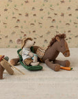 Maileg Pony Small with mouse in a hat, lantern, carrot, and fishing gear on a beige mat; playful nursery decor.