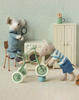 Maileg mouse fixes Abri a Tricycle as another watches in a vintage room with cabinet and washer, playful decor style.