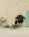 A small bedroom scene shows a Maileg mouse doll in bed with four Maileg Alarm Clocks, a metal chair, wardrobe, stool, and tiny suit on floral wallpaper.