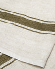 The Caravan Marseille Linen Towel Set-2 features rustic beige towels with two dark green stripes and a thinner parallel stripe, showcasing their textured weave and elegant design in a close-up view.
